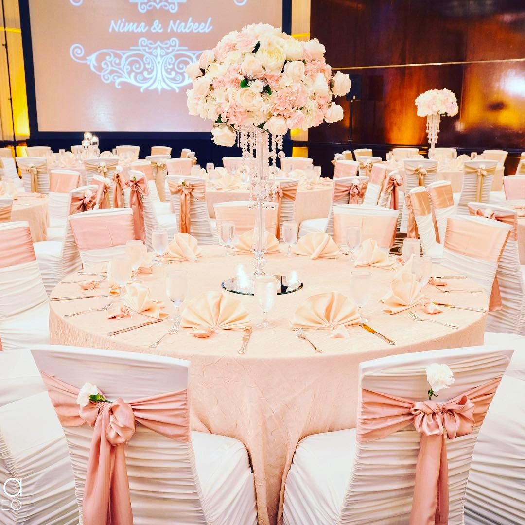 Blush wedding reception with pink chair sashes and tall floral centerpieces