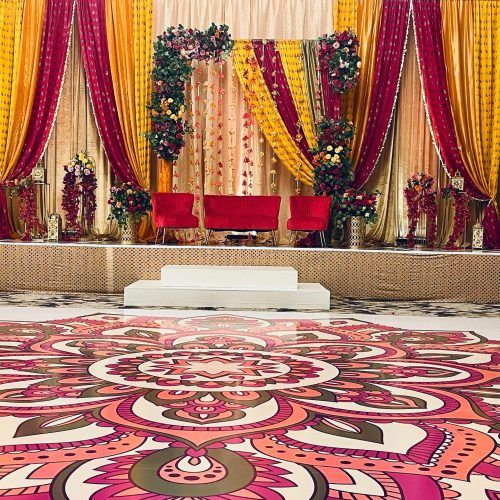 Colorful Mehndi stage with draped fabric and a patterned floor