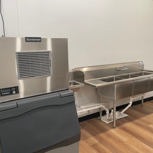 Ice machine beside a three-compartment sink