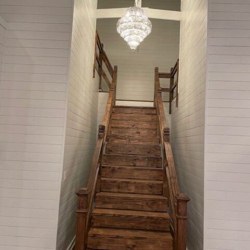 Rustic wooden staircase under a chandelier